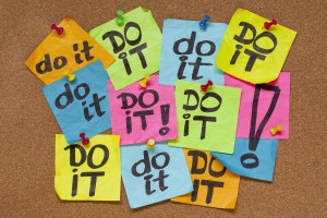 Fight procrastination concept - do it phrase on color sticky notes posted on a cork bulletin board